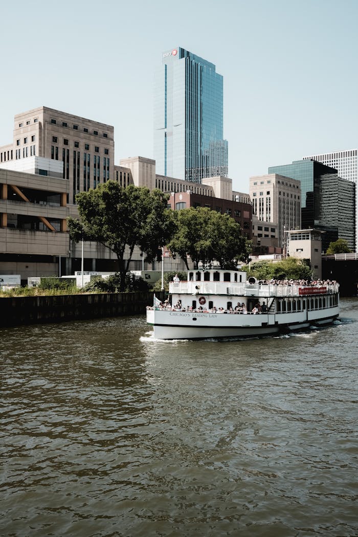 White riverboat cruising on the Chicago River against a backdrop of modern skyscrapers.